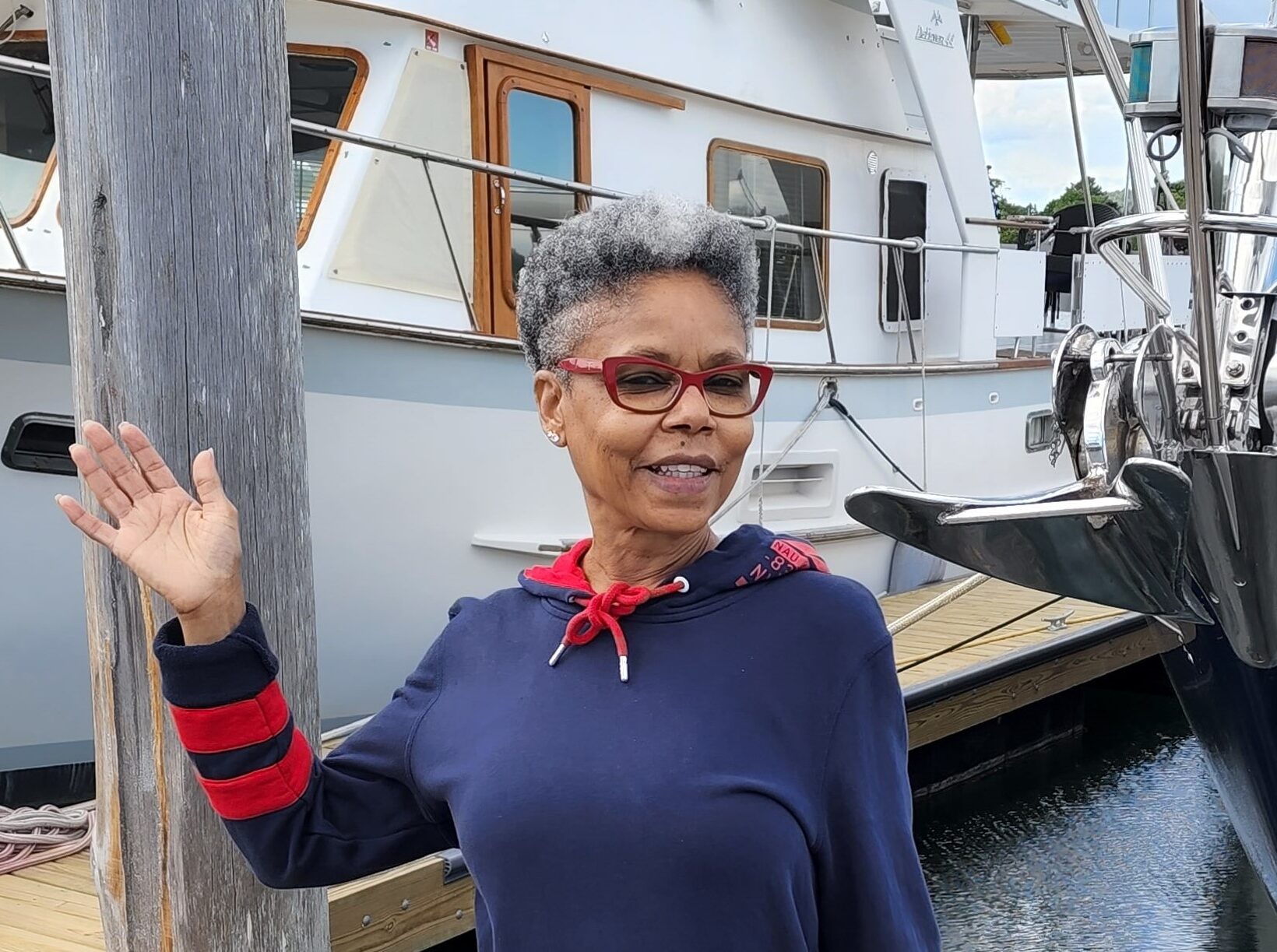 Debbie, a travel nurse, waving while standing in front of a boat